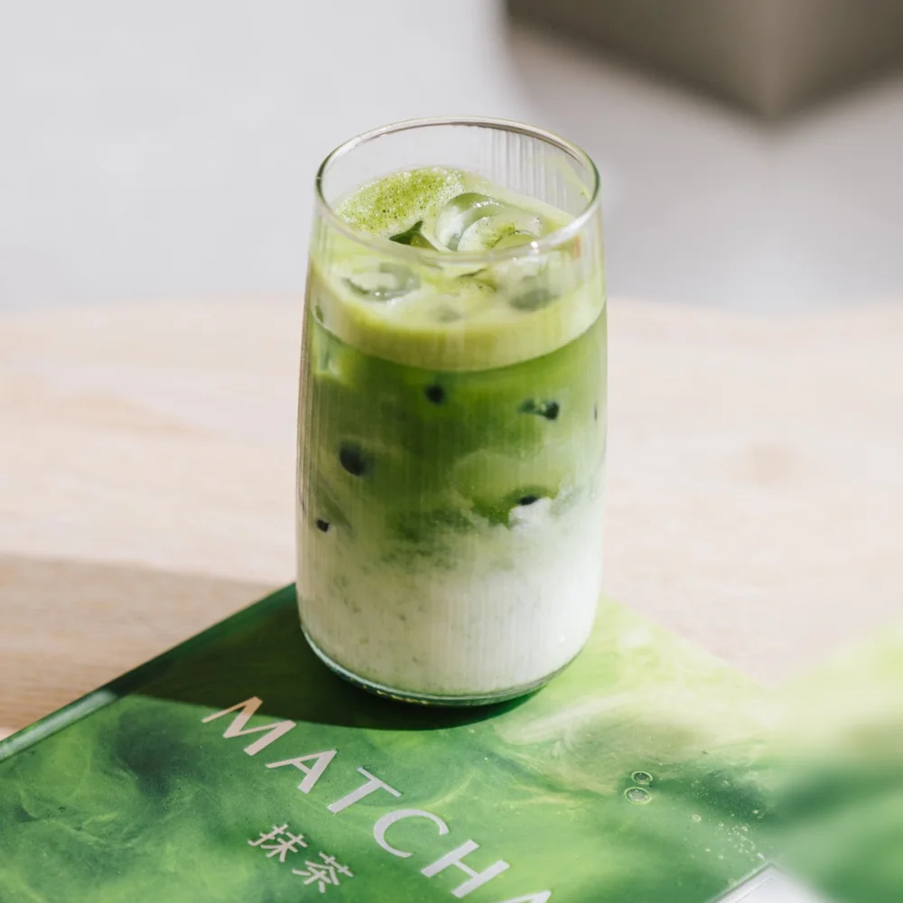 Iced matcha latte in a ribbed glass on a matcha cookbook